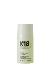 A bottle of K18 Leave-In Molecular Repair Hair Mask on a yellow background.