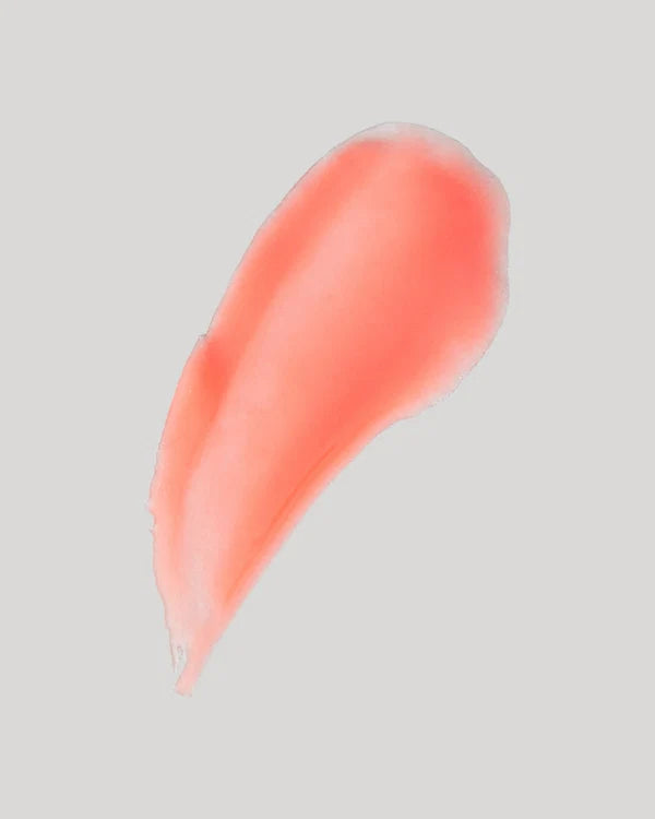 Smeared coral-colored makeup product on a gray background