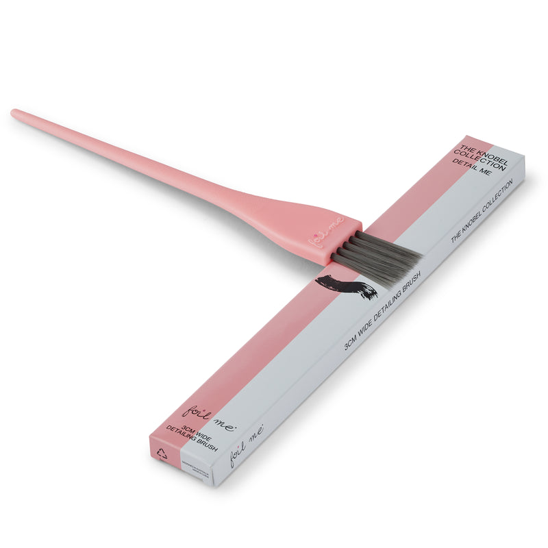 Pink hair dye brush with open box on a white background