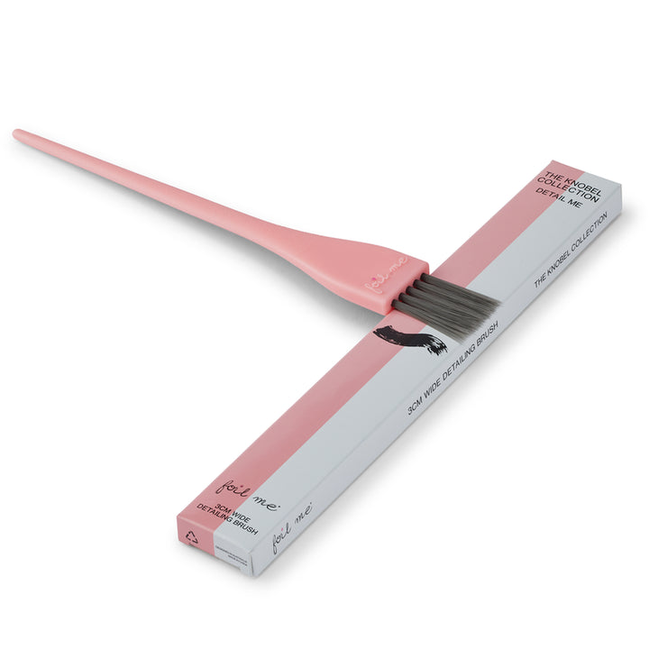 Pink hair dye brush with open box on a white background