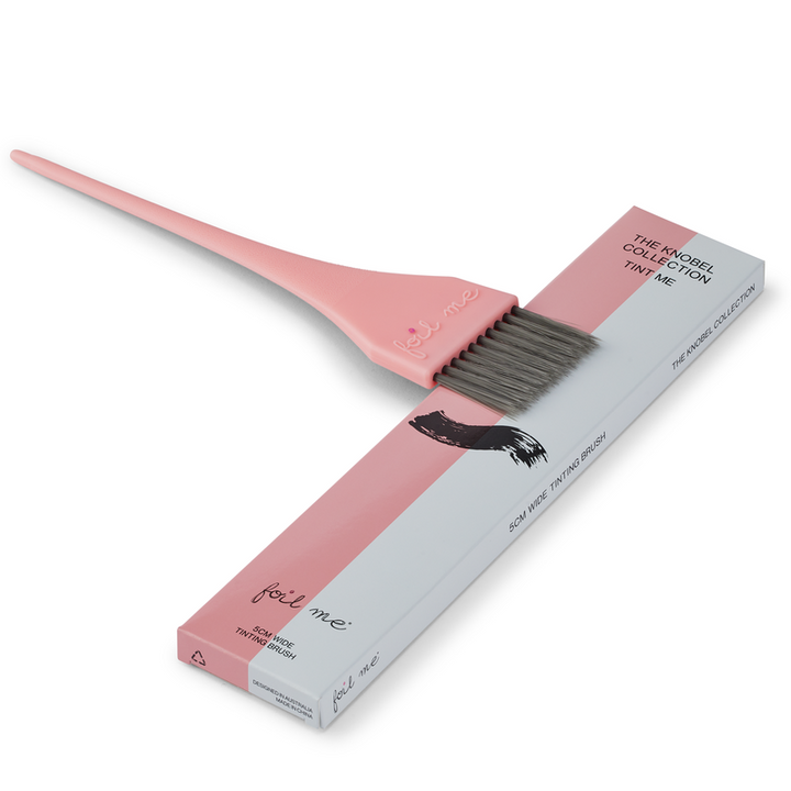 Pink hair dye brush with gray bristles and its packaging on a white background