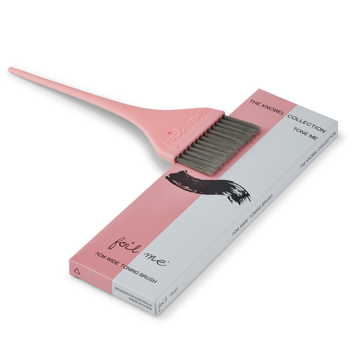 Pink tint brush with gray bristles and its packaging on a white background